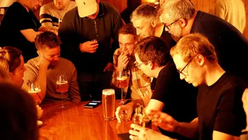 Gruppe Menschen schaut auf ein Handy in Bar.