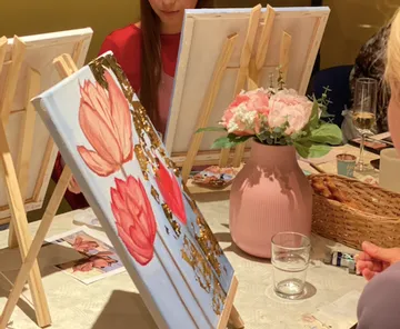 People painting flowers in a group setting.