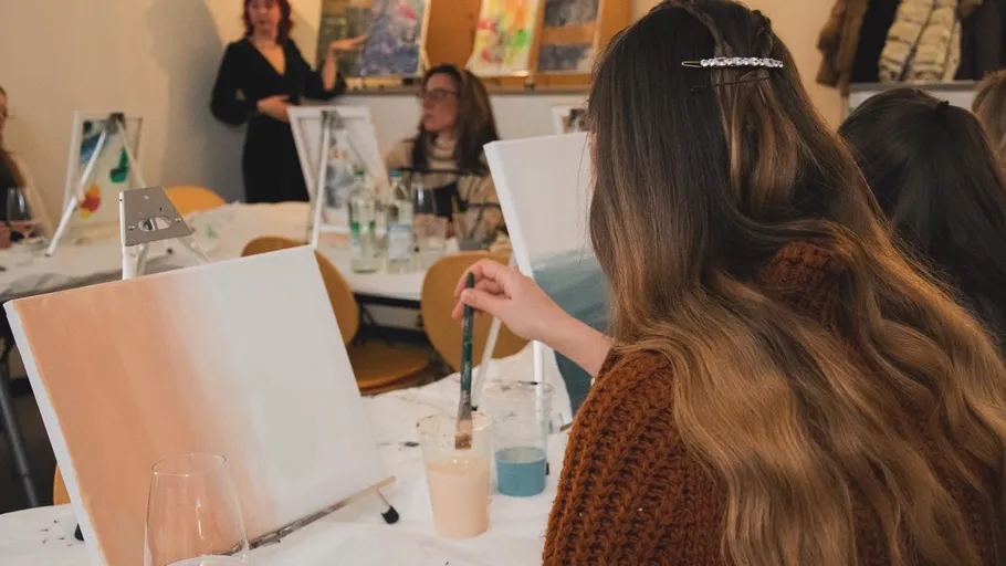 Woman painting canvas in art class setting.