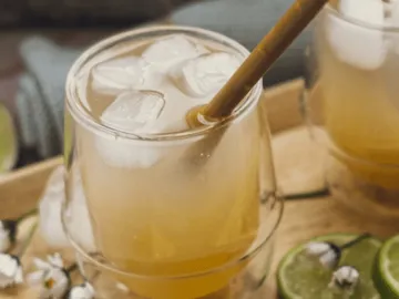 Glas mit Eiswürfeln, Getränk wird auf Holztablett serviert.