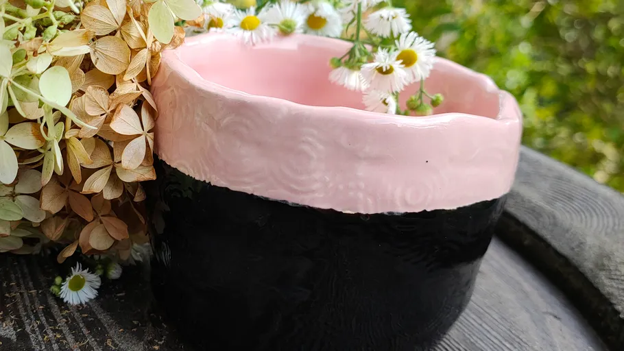 Zweifarbige Keramikschale mit Blumen im Freien.