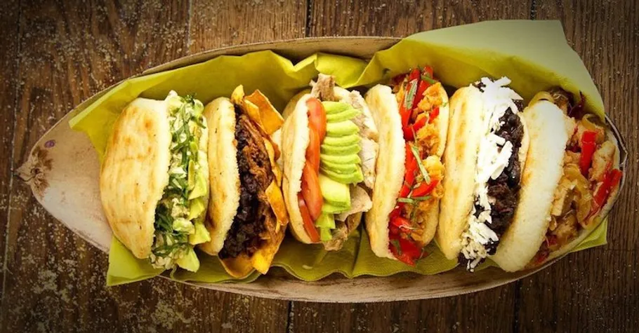 Five flavorful arepas in a wooden tray.