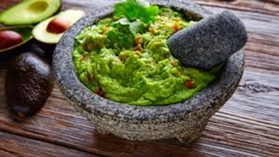 Guacamole im Steingefäß auf Holztisch.