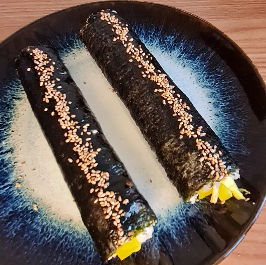 Zwei Kimbap-Rollen auf einem dekorativen Teller.