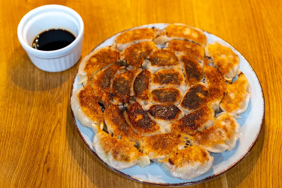 Fried dumplings on plate with soy sauce.