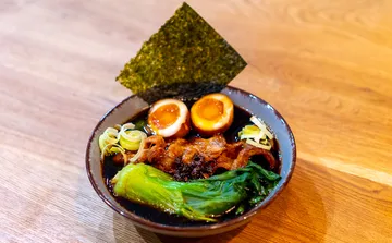 Bowl of ramen with eggs and greens.