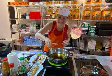 Person kocht in Küche, lächelt, bereitet Essen zu.