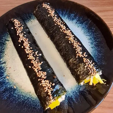 Zwei Sushirollen auf einem dekorativen Teller.