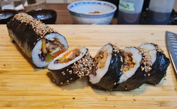 Sushirollen mit Sesam auf Holzbrett.