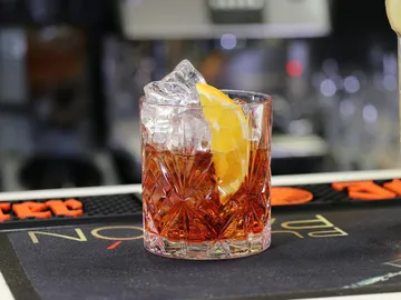 A cocktail glass with ice and an orange slice.