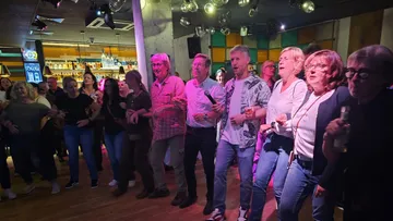 Gruppe singt bei einem lebhaften Bar-Event.
