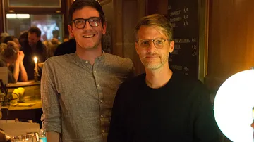Two men smiling in a dimly lit bar.