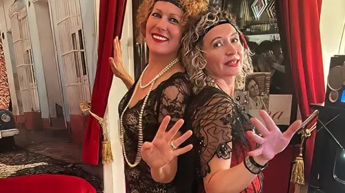 Zwei Frauen posieren in Vintage-Kostümen drinnen.