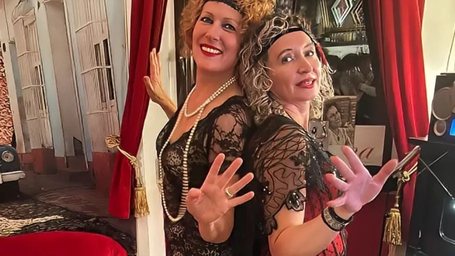 Zwei Frauen posieren in Vintage-Kostümen drinnen.