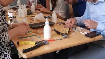 Menschen basteln an einem Tisch mit Werkzeugen.