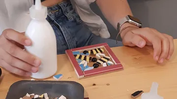 Hände erstellen Mosaik auf Holztisch.