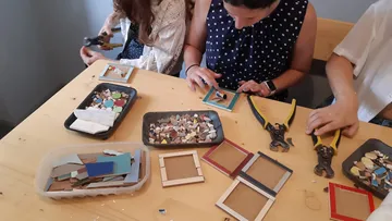 People crafting mosaic frames at a table.