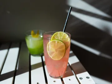 A pink cocktail with lime on a table.