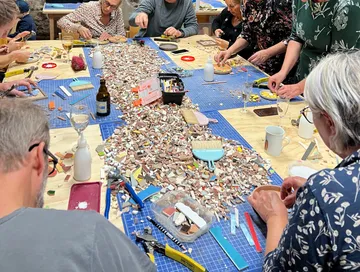 Menschen erstellen Mosaike an einem Tisch.