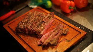 Seasoned steak slices on wooden cutting board.
