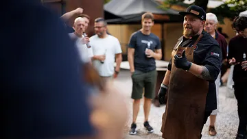 Man in apron speaks to a gathered group.