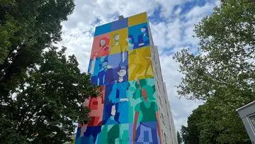 Colorful mural on tall building surrounded by trees.