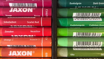 Bunte Wachsmalstifte im Kasten nach Farben sortiert.