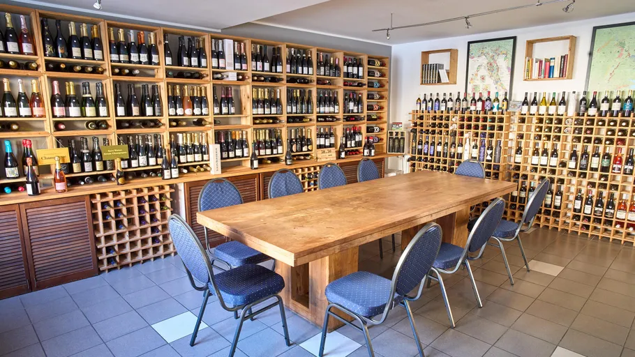 Wine bottles on shelves around wooden table.