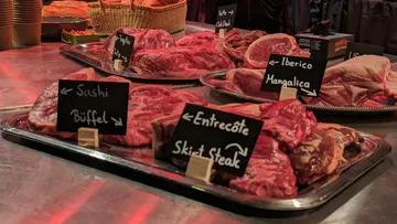 Various meats displayed with labels on tables.