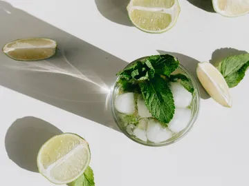Getränk mit Eis und Minze, umgeben von Limettenhälften.