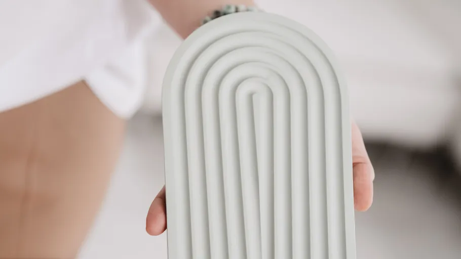 Person holding textured, arch-shaped object indoors.