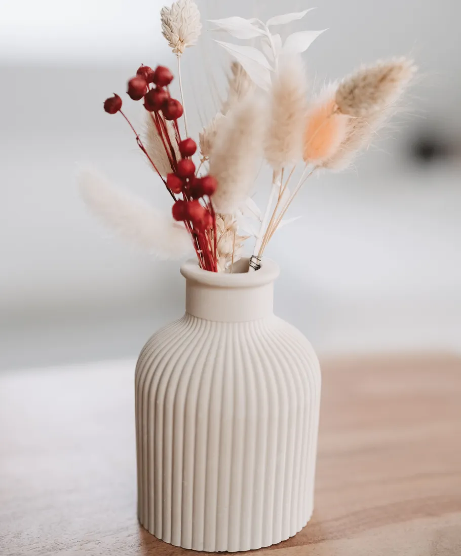 Cream vase with dried flowers on table.