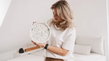 Woman holding a decorative plate indoors.