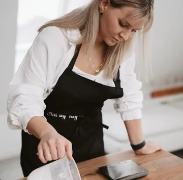 Woman pouring liquid in kitchen setting.