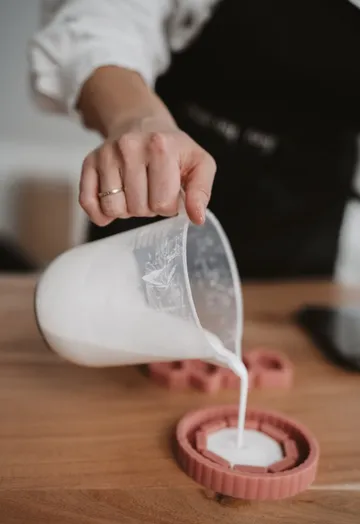Hand pouring liquid into a pink mold.