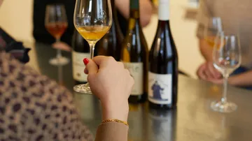 People holding wine glasses at tasting event.