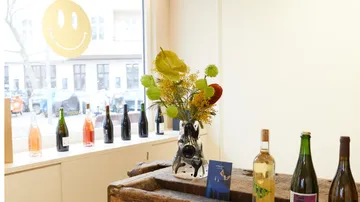Bottles and vase with flowers on a wooden table.