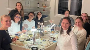 Gruppe von Frauen lächelt am Esstisch.