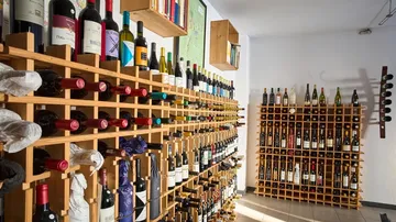 Weinflaschen in Holzregalen im Keller.