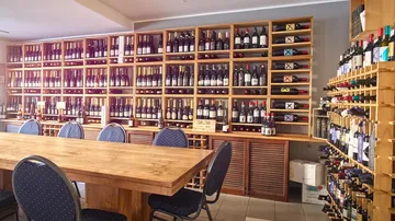 Wine bottles displayed on wooden shelves in shop.