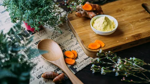 Kurkuma-Wurzel und Pulver auf Holzbrett.