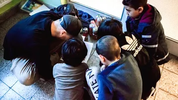 Group sitting on floor reading in hallway.