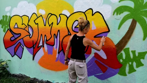 Person spray paints colorful graffiti wall.
