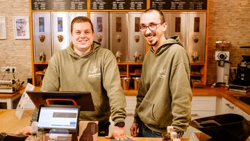 Two men smiling in a coffee shop.