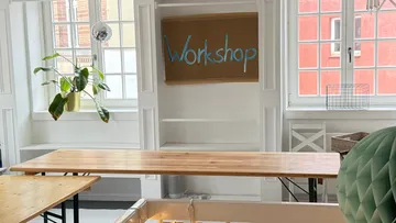 Holztische in hellem Workshop-Raum.