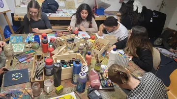 People painting at a table with art supplies.