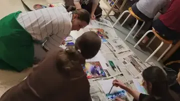 People painting on the floor using newspapers.