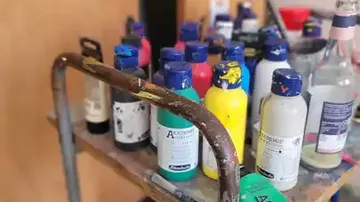 Paint bottles on a cart in a studio.