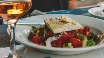 Colorful Greek salad and wine on table.