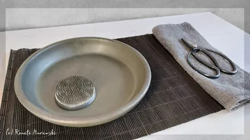 Metallteller mit Steckigel auf einer Matte.